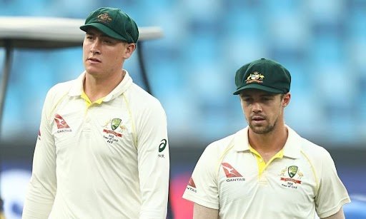 Australian cricketer Cameron Green wearing a white Test uniform and green baggy cap, walking on the field during a match.