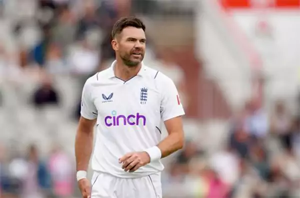 James Anderson wearing England cricket whites walking on the field during a Test match holding his shirt and looking focused