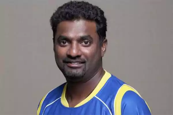 Muttiah Muralitharan wearing a blue and yellow cricket jersey holding 1347 international wickets